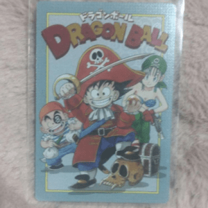 Dragon Ball card/cover showing Goku in pirate outfit with sword, Bulma behind him, Krillin on the left, a skull and treasure chest nearby on a blue-bordered card  Articulos Japan (Post Box Japan)