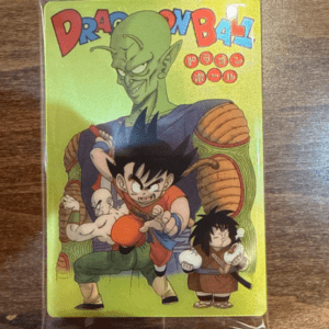 Bright yellow Dragon Ball Z card featuring Goku in orange, with Piccolo behind and other characters at his sides, wrapped in plastic.  Articulos Japan (Post Box Japan)
