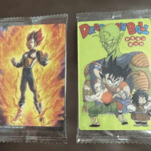 Two Dragon Ball trading cards in protective sleeves: Vegeta with fiery aura on the left and a green-covered card featuring Goku and friends on the right.  Articulos Japan (Post Box Japan)