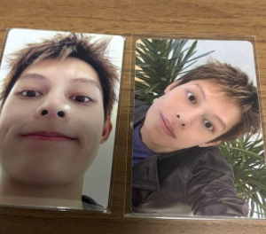 Two teen boys' selfies in a small side-by-side photo booklet on a wooden table.
