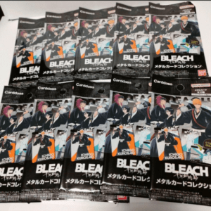 Collection of Bleach metal card packs spread out on a table, showing multiple glossy black packages with anime characters and Japanese text.