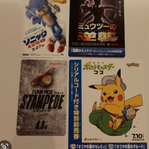 Four posters mounted on a light wall: top-left Sonic the Hedgehog movie poster (Japanese), top-right Pokémon: Mewtwo Strikes Back Evolution poster (Japanese text), bottom-left One Piece Stampede poster (Japanese), bottom-right Pokémon Pocket Monsters Pikachu poster with a hat (Japanese text).