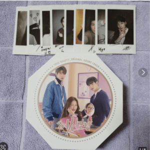 Polaroid photo strip with eight vertical photos laid over a purple towel, above a hexagonal album cover showing three people posing indoors with pastel colors.