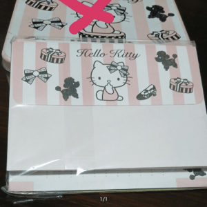 Hello Kitty themed gift box with pink vertical stripes, bows, and small presents, partially covered by a pink X mark graphic.