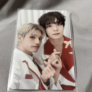 Two young men pose closely for a photo, wearing white outfits with red accents.