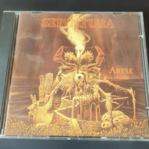 Sepultura Arise album cover: a gold-toned, skeletal monument erupting in flames with ruins around it.
