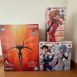 Boxed anime figure set: large orange A figure box on the left and three smaller boxes featuring female characters on the right (blue, white, and pink/red outfits).