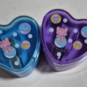 Two translucent heart-shaped containers in blue and purple with Care Bears designs on the lids, placed side by side on a white surface.