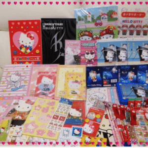 A collection of Hello Kitty stationery and small gifts arranged on a sofa, including colorful notebooks, cards, and packaging with pink borders.