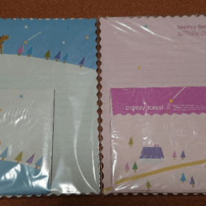 Two Breezy Forest notebooks laid side by side: left is blue with a snowy hill, small trees and animals; right is pink with a winding path and trees, both wrapped in plastic.