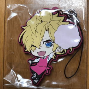 Chibi anime girl with blonde hair and blue eyes, wearing a pink apron, winking and posing with a puff of steam/cloud near her mouth, attached to a black strap as a keychain charm in plastic packaging.