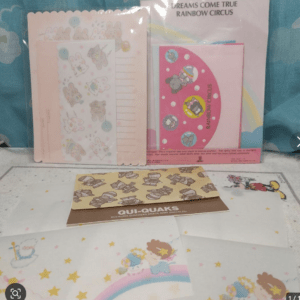 Colorful stationery set with pink envelopes, bunny stickers, and 'Dreams Come True Rainbow Circus' designs on a blue background.