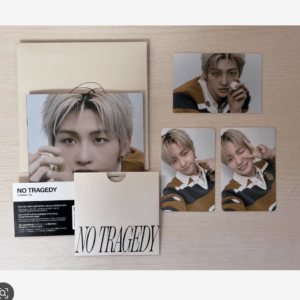 K-pop photo card set titled 'NO TRAGEDY' with portrait cards and an envelope on a light wood surface.