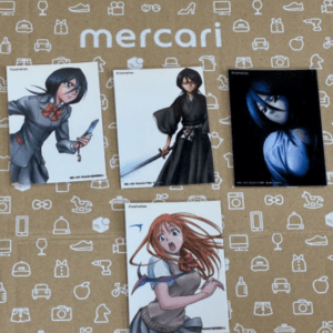 Mercari-branded box topped with four anime illustration cards featuring female characters.