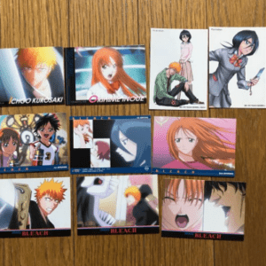 A collage of Bleach character cards laid on a wooden surface, featuring Ichigo, Rukia, and others.