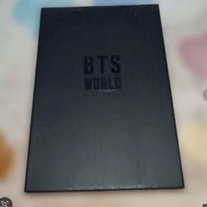 Black BTS World Limited Edition box resting on a blurred pastel background. The matte black packaging features embossed BTS WORLD branding on the lid.