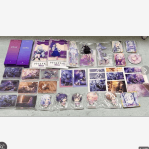 Assorted anime merchandise laid out on a floor: acrylic standees, cards, and purple-packaged boxes featuring anime characters, neatly arranged for display or sale.