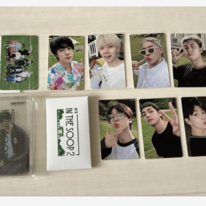 Set of BTS photo cards laid out on a light table, featuring multiple members posing for selfies and a white box labeled 'IN THE SOOP2' in the center-left pocket