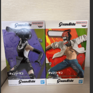 Two Grandista action figure boxes on a shelf, each featuring a character with a chainsaw-style head: the left box shows a purple-themed figure in a black outfit, the right box shows a figure in a white jacket and jeans with a red chainsaw head.