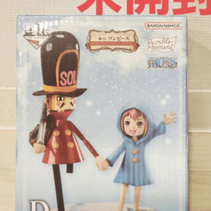 Boxed action figures: a small girl in a blue coat waving beside a tall toy soldier in a red outfit and tall black hat, from the Revive Moment series by Bandai Namco.