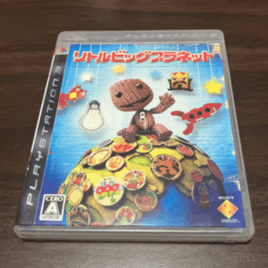 PlayStation game case for LittleBigPlanet with Sackboy figurine atop a colorful patchwork globe on a blue background.