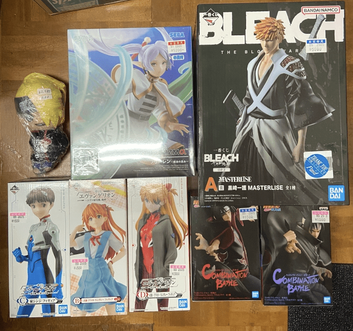 Captura De Pantalla 2026-06-04 a Las 180913 - Articulos Japan (post Box Japan) Assorted anime figure boxes and a loose toy on a wooden floor, including a Bleach character box and a Haku or idol-themed box. Articulos Japan (Post Box Japan)