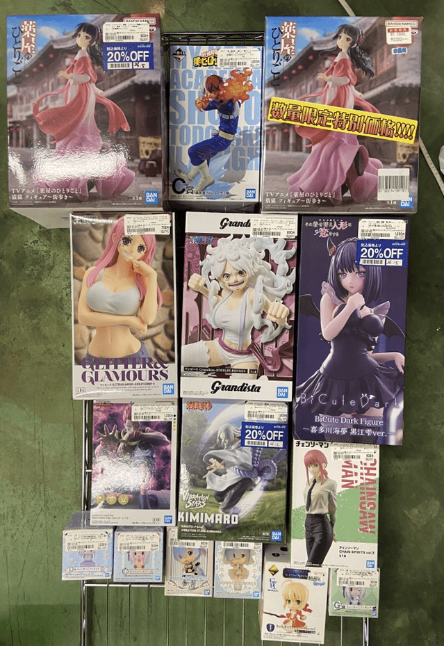 Captura De Pantalla 2026-06-29 a Las 191426 - Articulos Japan (post Box Japan) Rack display of multiple anime figure boxes featuring characters in colorful outfits (pink dress, blue action pose, white-haired fighter, and a purple-clad character). Articulos Japan (Post Box Japan)