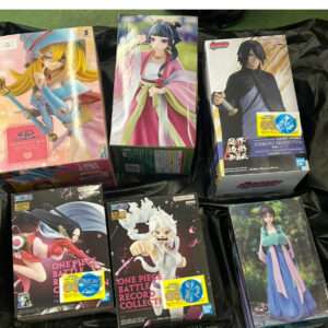 Collection of six anime figure boxes arranged on a black surface, showing colorful character art on the boxes.