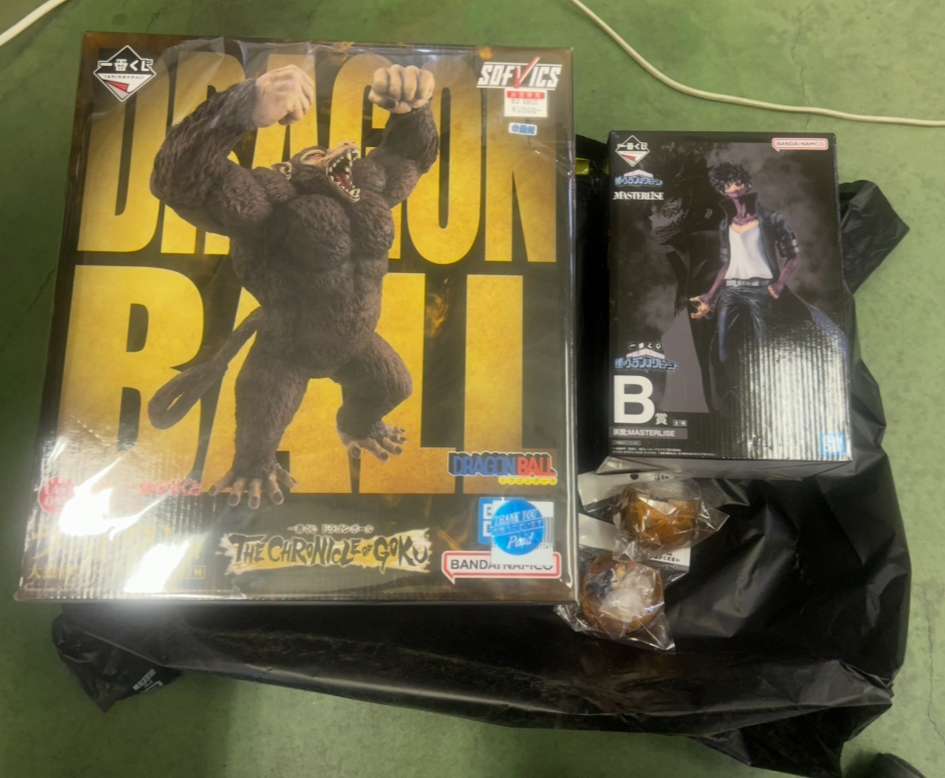 Img_0222 - Articulos Japan (post Box Japan) Dragon Ball merchandise box featuring a large Godzilla-like gorilla figure on a yellow background, with a black plastic bag beneath. Articulos Japan (Post Box Japan)