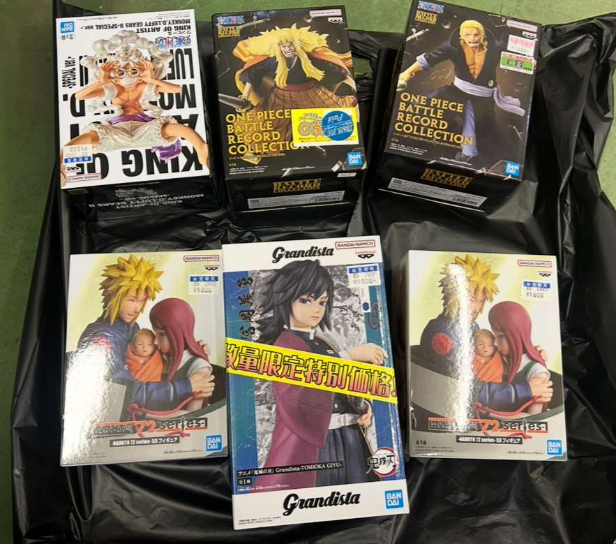 Img_0242 2 - Articulos Japan (post Box Japan) A collection of anime figure boxes arranged on a black plastic bag, including One Piece Battle Record Collection and Grandista figures featuring various characters. Articulos Japan (Post Box Japan)