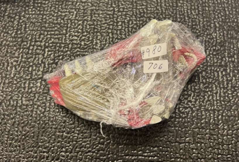 Img_0243 3 - Articulos Japan (post Box Japan) Small object wrapped in plastic with two label stickers reading #980 and 706 on a textured dark surface Articulos Japan (Post Box Japan)