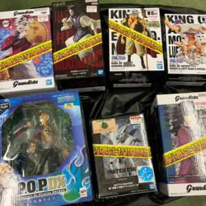 Collection of boxed anime figurines arranged on a black surface, including Grandista and POP! figures from One Piece and other series, with price stickers visible on the boxes.