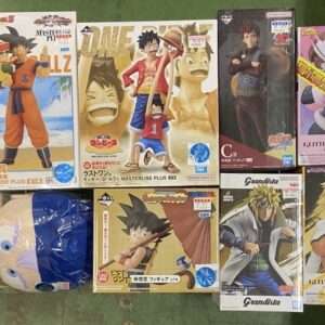 Collection of boxed anime figurines on a green floor, featuring Dragon Ball Z Goku and One Piece characters