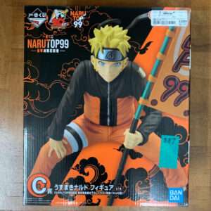 Box for a Naruto Top 99 figure showing Naruto in an orange jumpsuit holding a staff against a black-orange patterned background.  Articulos Japan (Post Box Japan)