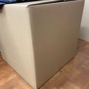 Large brown cardboard box on a wooden floor with flaps closed at the top edge of the box film-wrapped items resting on it (informative)