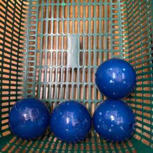 Four blue plastic balls resting in the bottom of a green perforated basket.