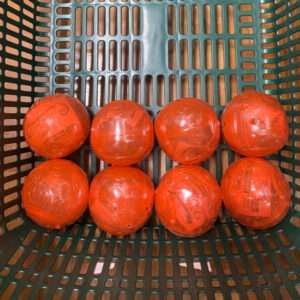 Eight orange plastic balls arranged in a green shopping basket.
