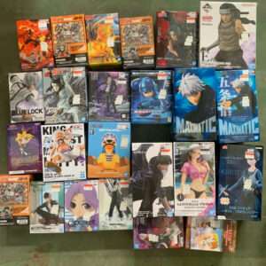 Collection of anime figure boxes arranged on a green floor, featuring Naruto, One Piece, and other character figures visible on the boxes.