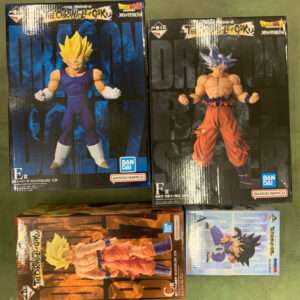 Four Dragon Ball Masterlise action-figure boxes on a green surface: two large black boxes showing Super Saiyan Goku figures, one orange-gi Goku at bottom left, and a small blue-box figure at bottom right.