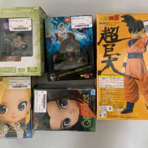 Boxed Dragon Ball Z collectible figures on a light surface, including a green box, a blue-vegeta figure, a large orange Goku box, and a Golden Frieza clock figure with price stickers visible.