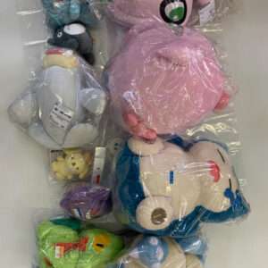 Assorted stuffed animals in clear plastic bags, including a large pink plush with big eyes and a blue and white penguin-like toy nearby.