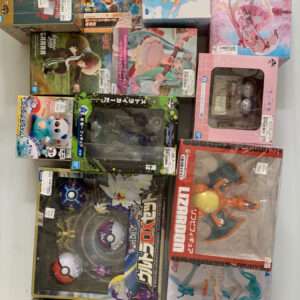Assorted anime and video game figure boxes stacked on a light surface, featuring Pokémon, Kirby, Dragon Ball, and other colorful packaging.  Articulos Japan (Post Box Japan)