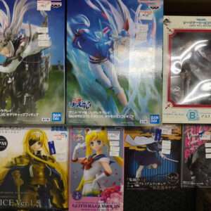 Boxed anime figures on a store shelf, front row shows a golden-haired character and a Sailor Moon figure, back row features dynamic action pose boxes in blue tones and a boxed figure with a red window.  Articulos Japan (Post Box Japan)