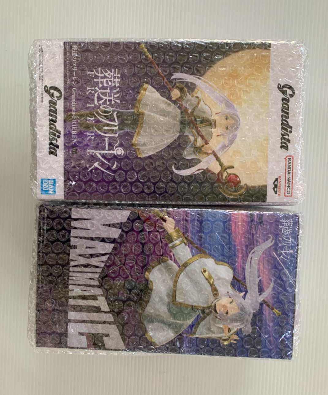Img_2076 - Articulos Japan (post Box Japan) Two anime figure boxes wrapped in bubble wrap; top box shows a girl with a staff against a purple gradient background. Articulos Japan (Post Box Japan)
