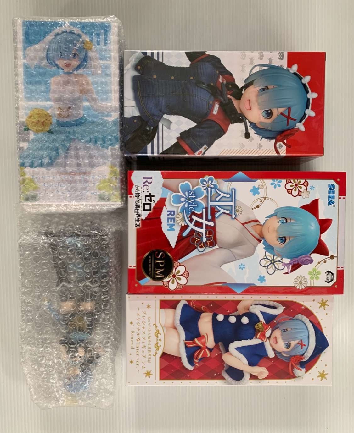 Img_2105 - Articulos Japan (post Box Japan) Stack of anime figure boxes with blue-haired character art, some wrapped in bubble wrap and one box featuring a nurse-style outfit and another in red-and-white with floral accents. Articulos Japan (Post Box Japan)