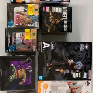 Assorted boxed anime action figures and model kits on a table, including Dragon Ball and One Piece sets with price stickers visible.