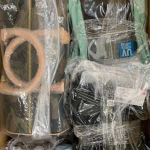 Assorted fashion bags and accessories tightly wrapped in plastic inside a cardboard box.
