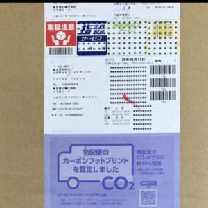 Shipping label on a cardboard box with barcodes, Japanese text, and a purple CO2 label about calculating the carbon footprint.