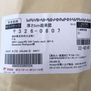 Japanese shipping label on a brown package with multiple barcodes, a large tracking number, and both Japanese and English sender/recipient details including Alexandra Rodriguez’s name and JP Post logo on the bottom left.  Articulos Japan (Post Box Japan)