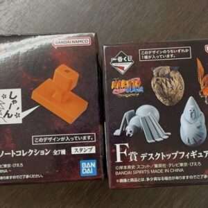 Two boxed hobby collectibles from Bandai Namco: left box shows an orange stand and manga-style speech bubble, right box features Naruto creatures art on a dark background.